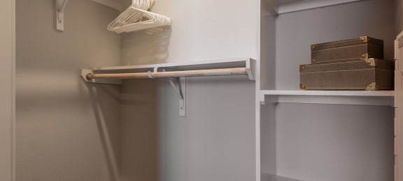 a walk in closet in a home with white shelves and grey walls