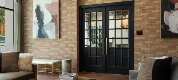 a living room with a black door and a brick wall