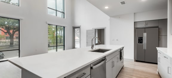 a kitchen with white countertops and a large white island with a stainless steel sink