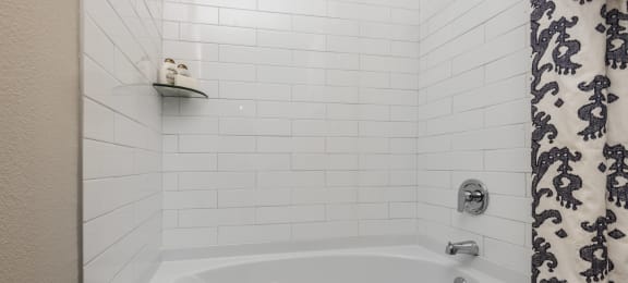 a white bathtub in a bathroom with a black and white shower curtain
