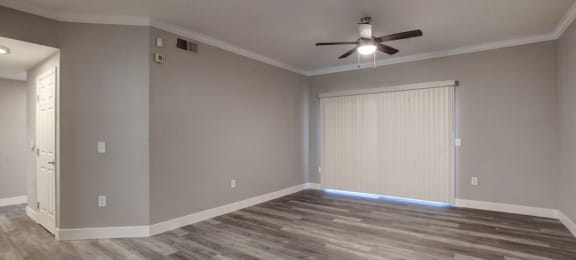 an empty living room with a ceiling fan