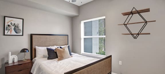 a bedroom with a large window and a ceiling fan