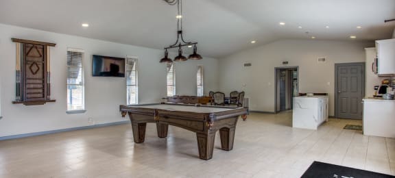 a large living room with a pool table and a kitchen