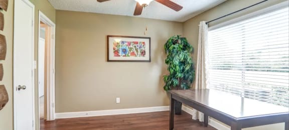 Hardwood like flooring with large window and ceiling fan.