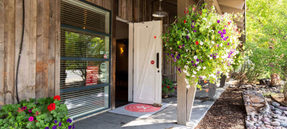 Front door of a wooden building with flowers in front of it at Mullan Reserve Apartments in Missoula, MT