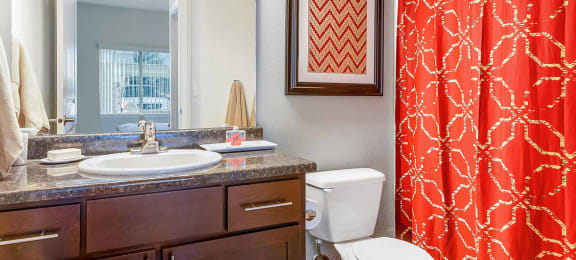 Bathroom with a red shower curtain, sink, and toilet