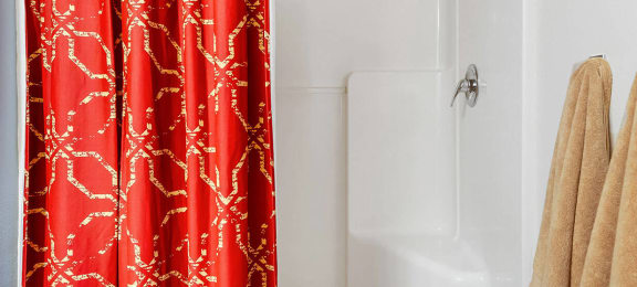 Bathroom with a red shower curtain and a white bathtub at Mullan Reserve Apartments, Montana, 59808