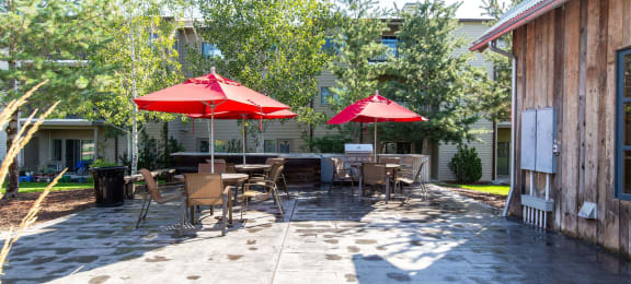 Patio with red umbrellas, tables, and chairs at Mullan Reserve Apartments in Missoula, MT