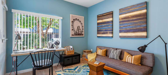A room with light blue walls, a couch, and a desk with a chair at Mullan Reserve Apartments