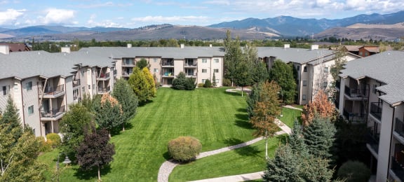Aerial view of an apartment complex with a lawn and trees