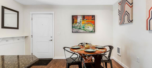 Dining area with a wooden table and chairs and a colorful painting on the wall at Mullan Reserve Apartments in Missoula, MT