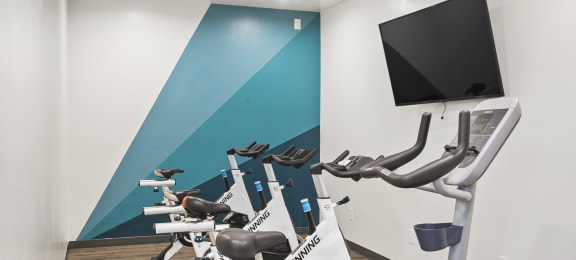 a group of exercise bikes in a gym with a tv