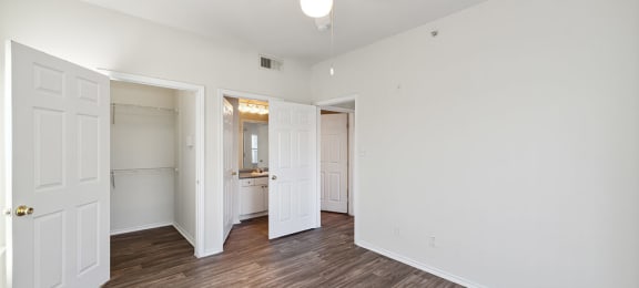 Two Bedroom Apartments in North Dallas TX - Tivoli - Well Lit Bedroom with Wood Plank Flooring, Oversized Closet, Large Windows, and En Suite Bathroom