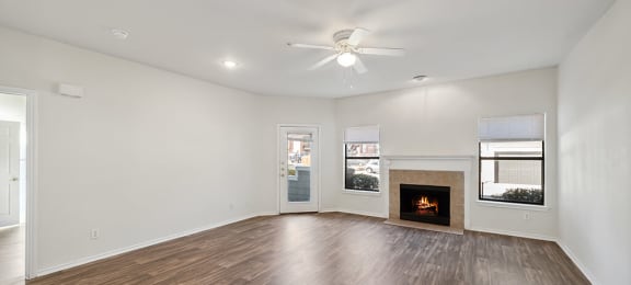 North Dallas Apartments for Rent - Tivoli - Open Concept Living Room with Tile Fireplace, Wood Plank Flooring, Large Windows, and Ceiling Fan