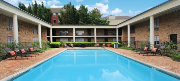 Apartments near the Galleria with multiple swimming pools, sun deck with poolside lounge chairs, brick exteriors and courtyard setting at Plantation apartments in Houston.