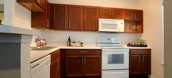 Spacious kitchen with designer white appliances and plank wood floors at Village on the Parkway Apartments.