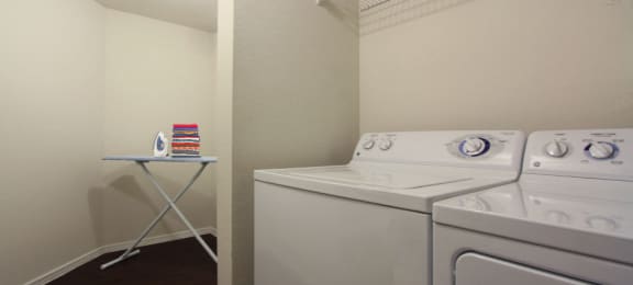 Spacious laundry area with full-size washer and dryer and extra storage space at Village on the Parkway Apartments.