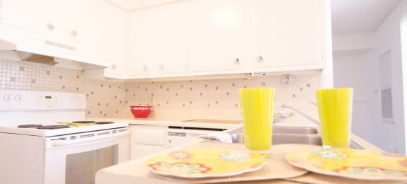 a white kitchen with yellow glasses on the counter