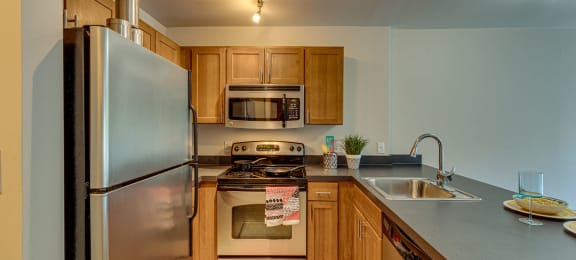 an updated kitchen with stainless steel appliances and wood cabinets