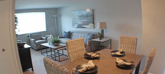 a dining room with a table and chairs and living room in the background  at Valley York Apartments, Ohio
