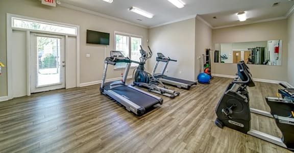 a gym with treadmills and weights and a tv
