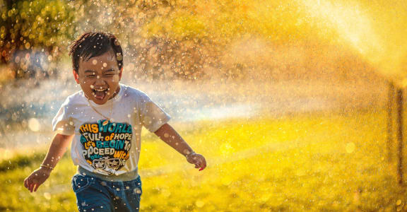 a young boy running through a spray of water