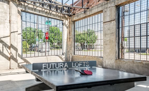 a ping pong table sits in front of a window with a street sign that reads fut