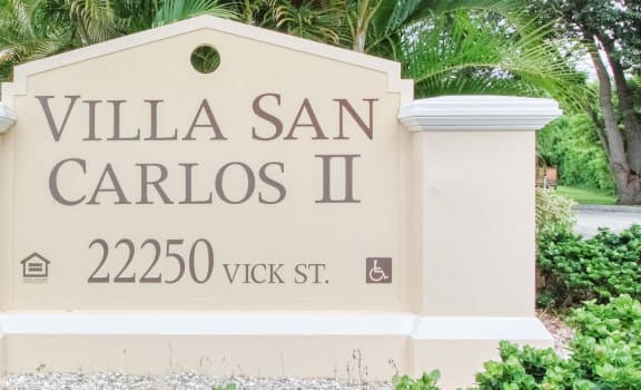Monument sign with Villa San Carlos II and address in front of community