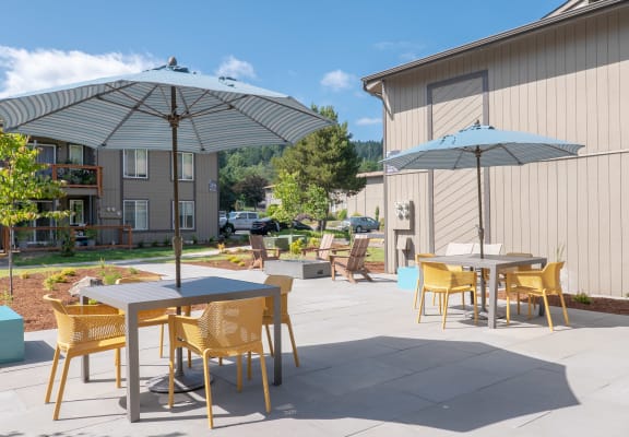 a patio with tables and umbrellas at the whispering winds apartments in pearland, tx