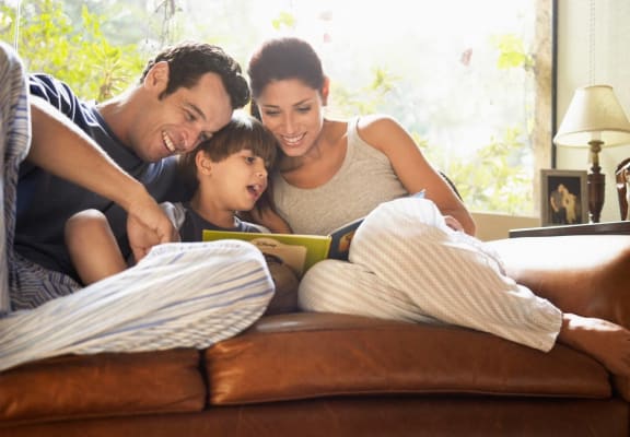 a family sitting on a couch reading a book