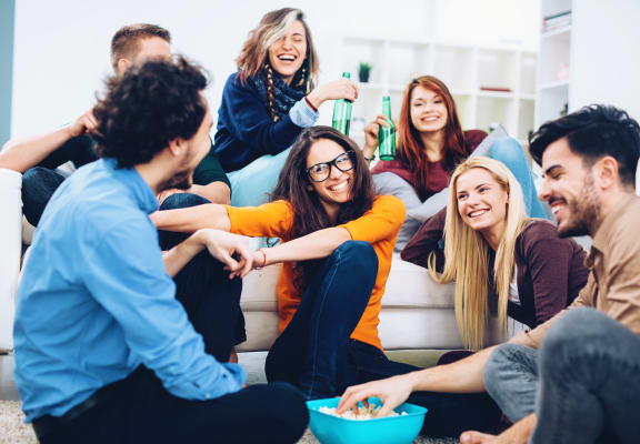 Large group of friends hanging out in apartment at Renew Five Ninety Five, Illinois, 60016