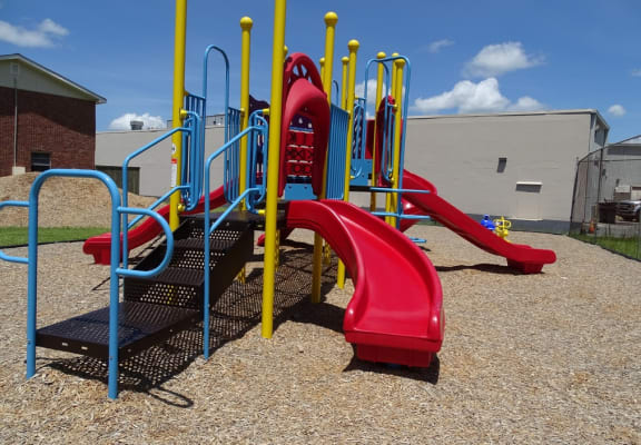 a playground with a red slide and blue and yellow slides