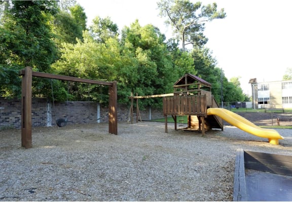 a playground with a wooden playset and a yellow slide