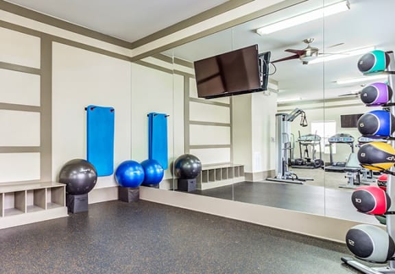 a spacious fitness room with exercise equipment and a flat screen tv