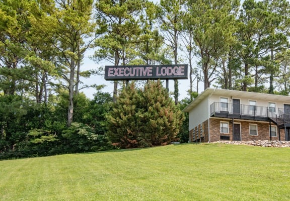 a building on a grassy hill with a sign that reads executive lodge