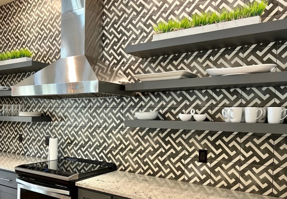 a kitchen with a stove and counters and a wall with a checkered wallpaper