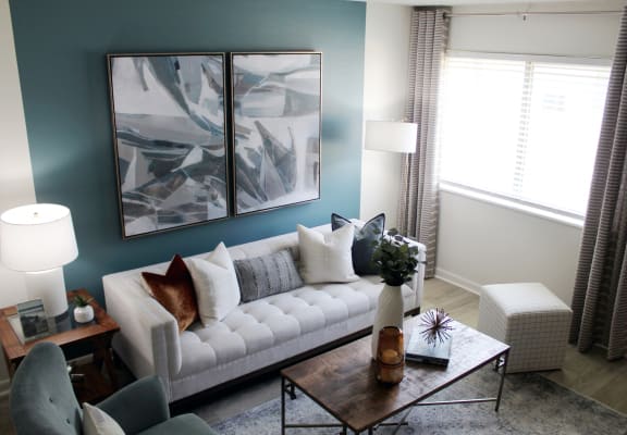 Living room with large window, model furnishings, and accent wall  at Huntsville Landing Apartments, Alabama, 35806