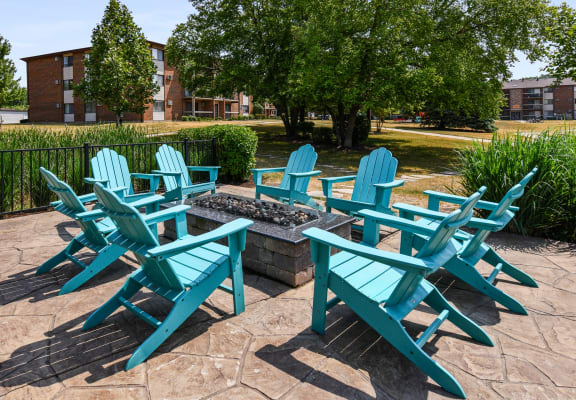 a patio with adirondack chairs and a fire pit