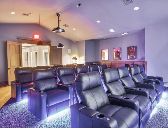 a theater room with blue leather chairs and purple walls