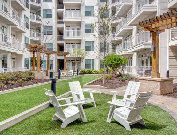 a courtyard with chairs and tables in front of an apartment building
