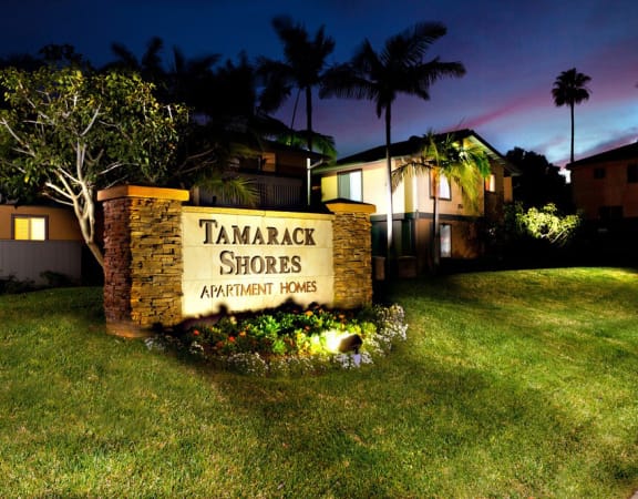 a sign for the tamarack shores apartments at night