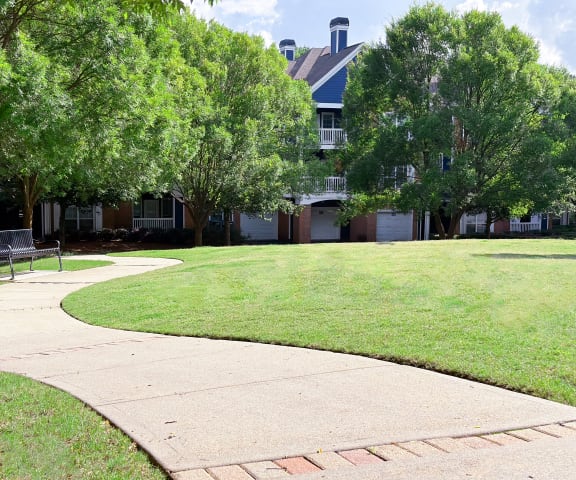 a sidewalk leads through a grassy area with a building in the background