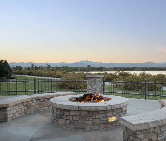 a fire pit and seating area on a patio with a view of a lake and mountains