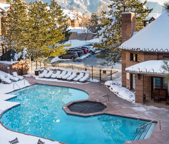 a swimming pool in the snow with mountains in the background