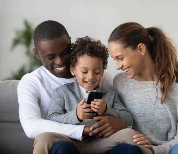 a family sitting on a couch looking at a cell phone