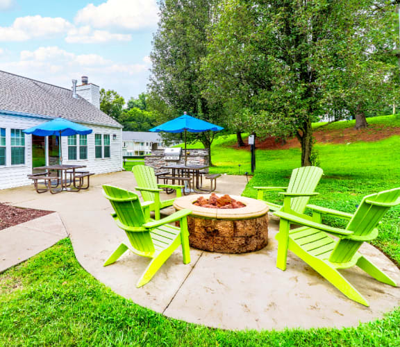 the backyard has a fire pit with green chairs and umbrellas