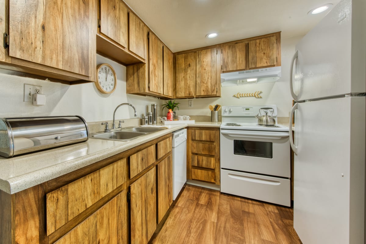 Kitchen with wood cabinets and white appliances — view 1 at Connect on Northern Apartments.