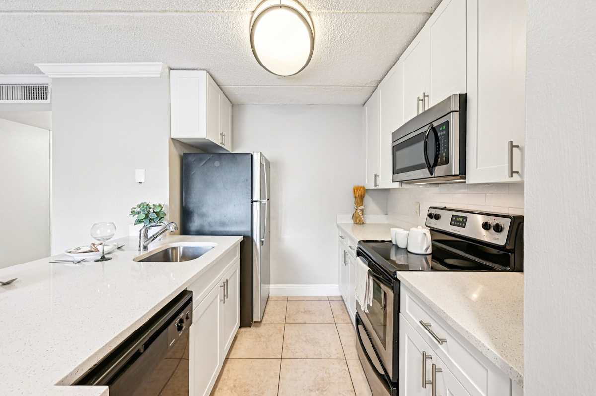 Palm Court at Wellington Apartments kitchen with white cabinetry - Wellington, FL