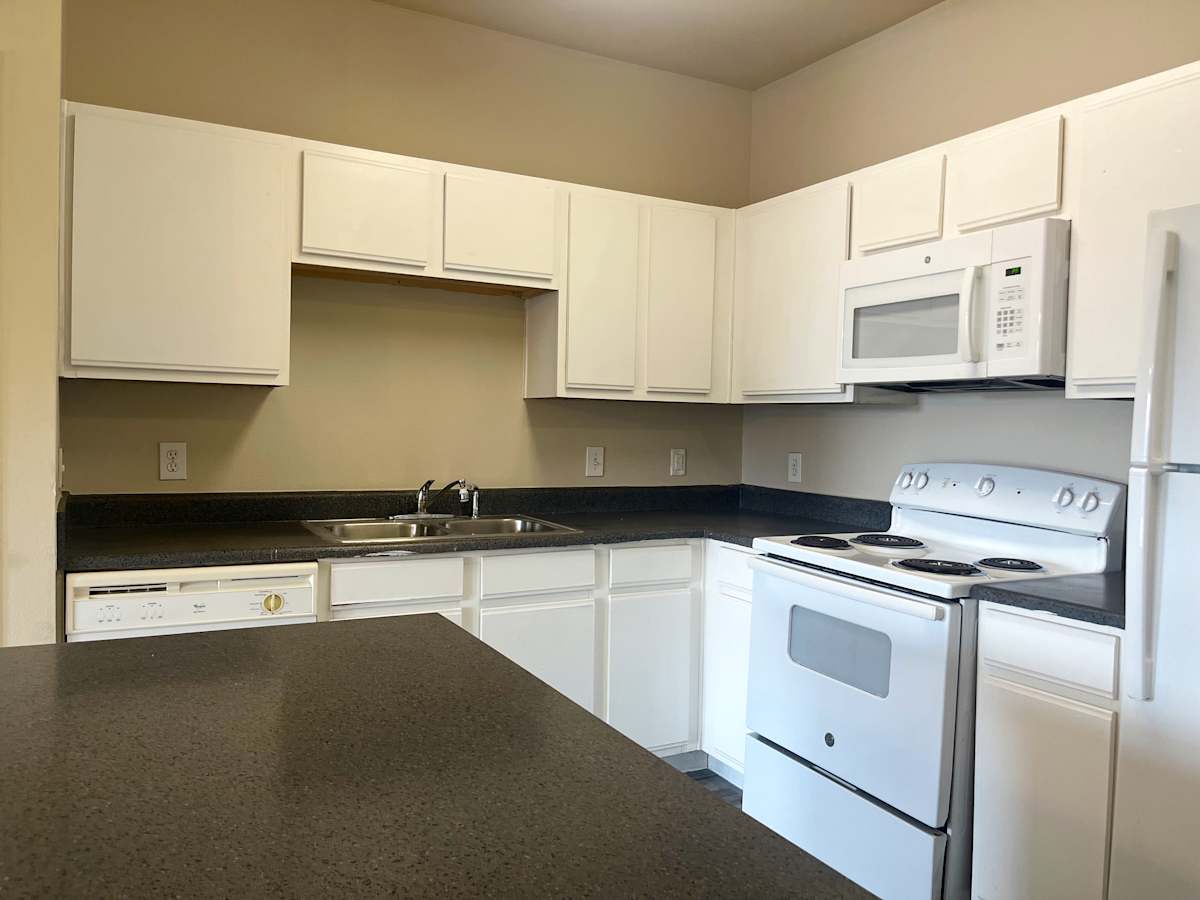 Refugio Place kitchen with white appliances and cabinets - San Antonio, TX