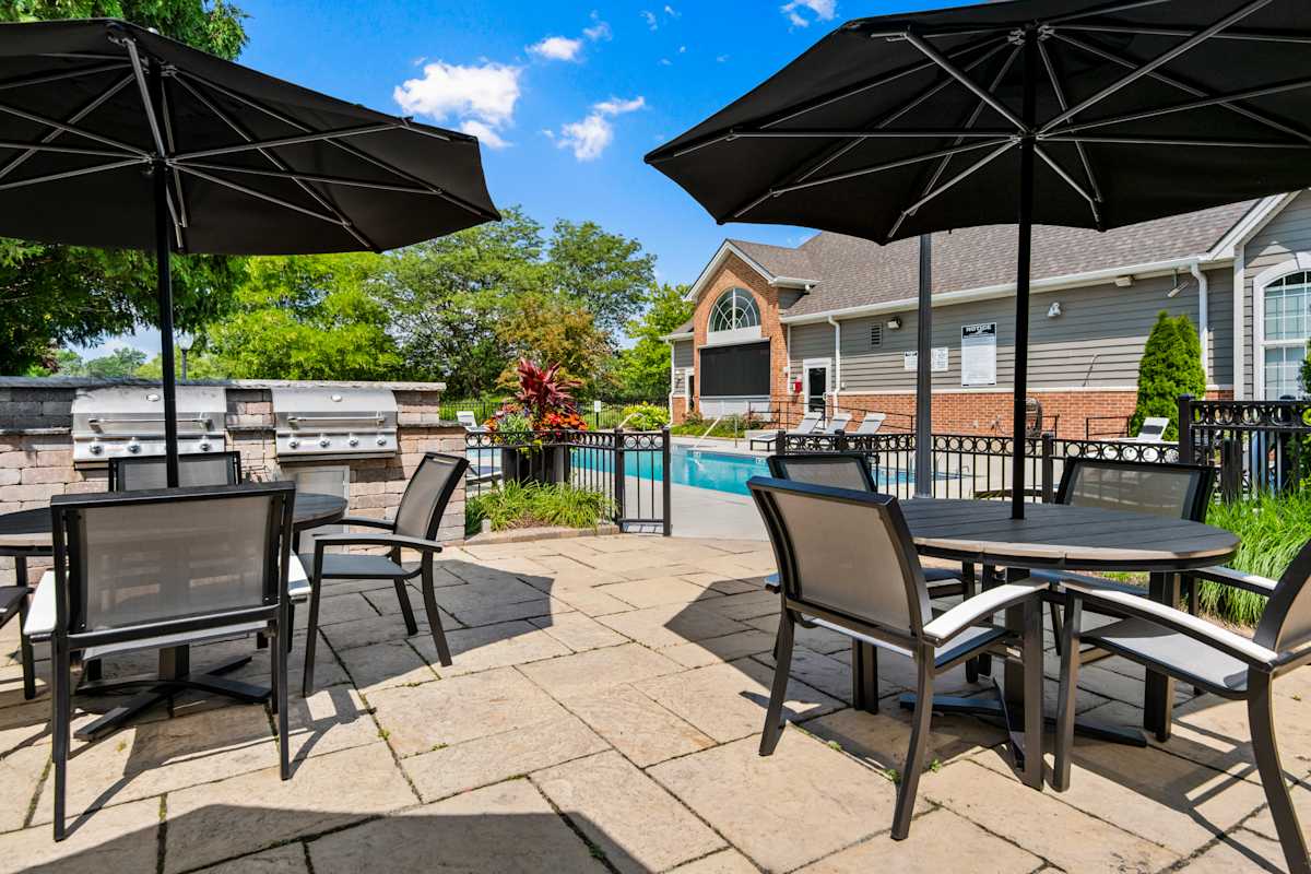 The Retreat at Seven Bridges poolside patio with tables and umbrellas - Woodridge, IL